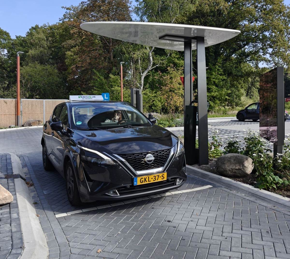 Zwarte Nissan Qashqai lesauto van rijschool i12drive.nl met L-bord op het dak